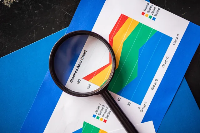Magnifying glass highlighting stacked area charts for business analysis. Seven measurement cost categories for England buyers to model outside a licence quote