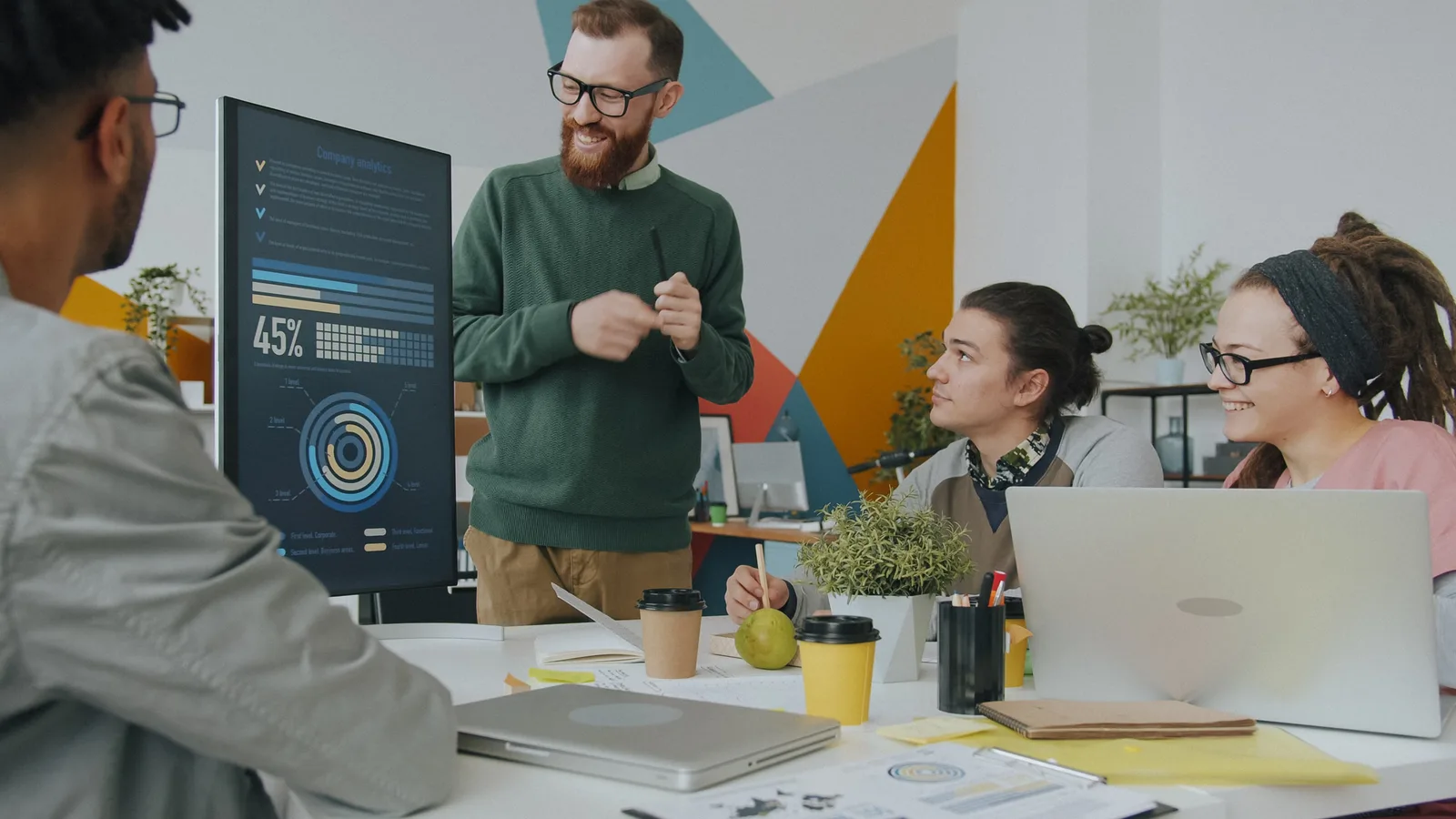 A diverse team engaged in a business meeting, analyzing company metrics on a presentation board.