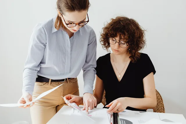 Two businesswomen reviewing documents at a workspace, focusing on collaboration and teamwork. A proposed Matomo launch in England, reviewed at the desk and held