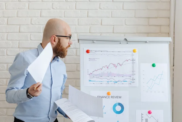 Bald businessman in smart casual attire analyzing financial charts on a whiteboard in an office setting. Six stop conditions for a privacy first measurement report, and how to re-release